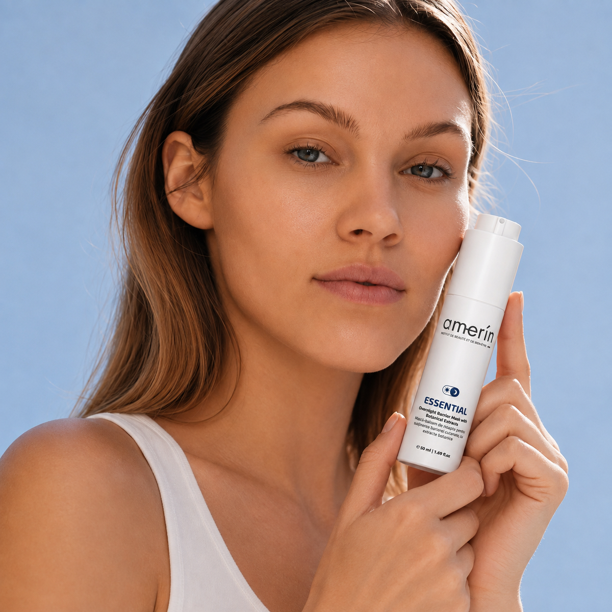 A woman with natural skin holding a white AmeriSkin Essential Moisturizer bottle against a solid blue background.