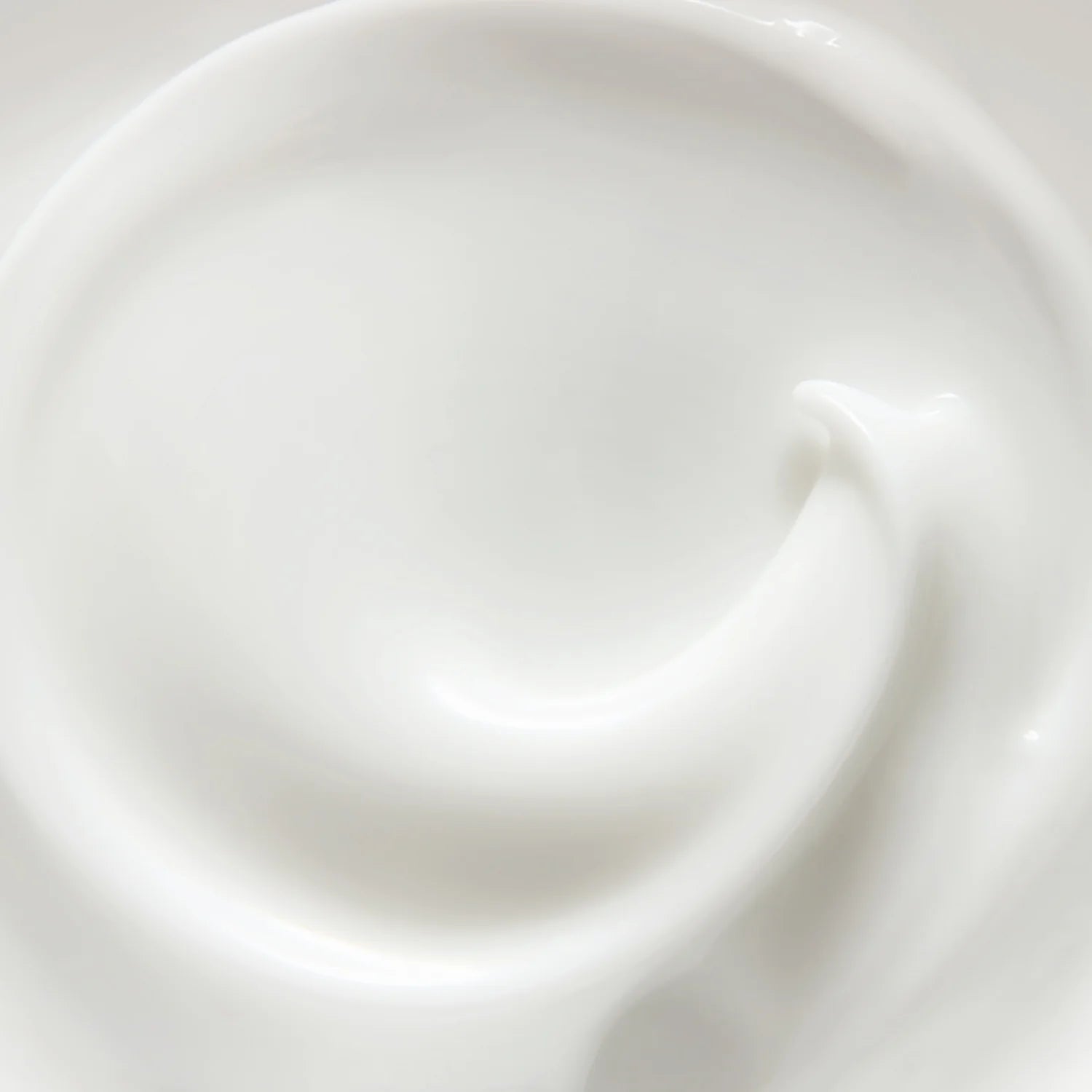 A close-up of a smooth, creamy white product, likely a skincare cream or lotion, swirled in a circular motion.